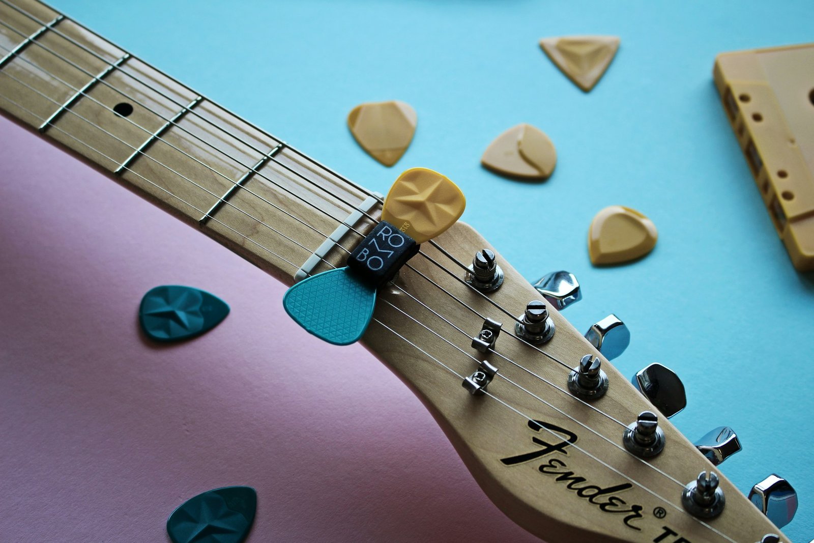A clip-on tuner on a guitar headstock with picks around it