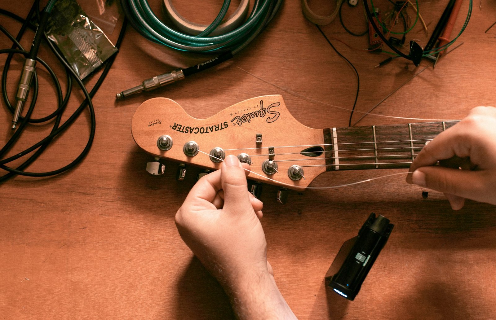 Hands fitting new strings on an electric guitar headstock