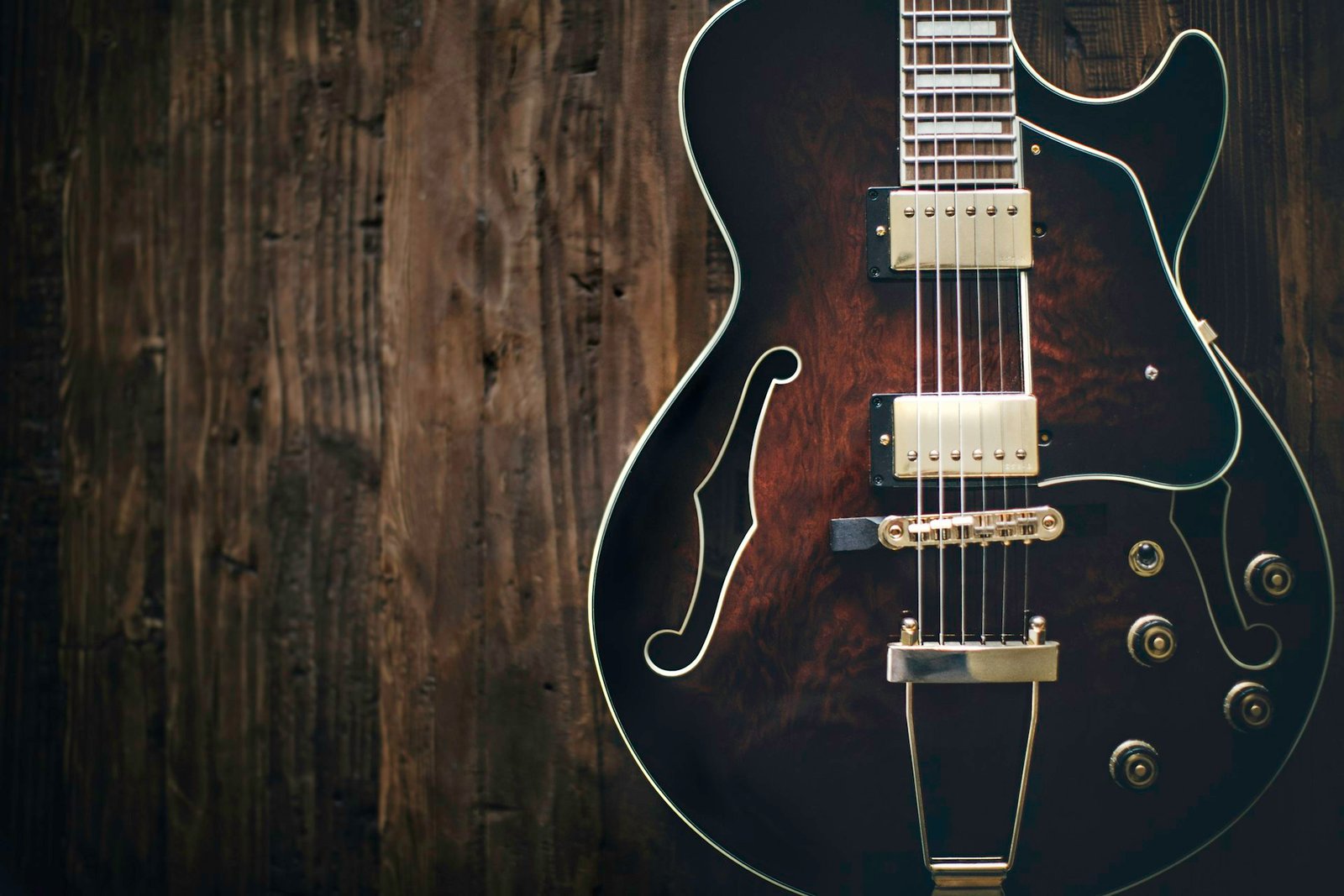 A semi-hollow electric guitar with f-holes on a wooden background