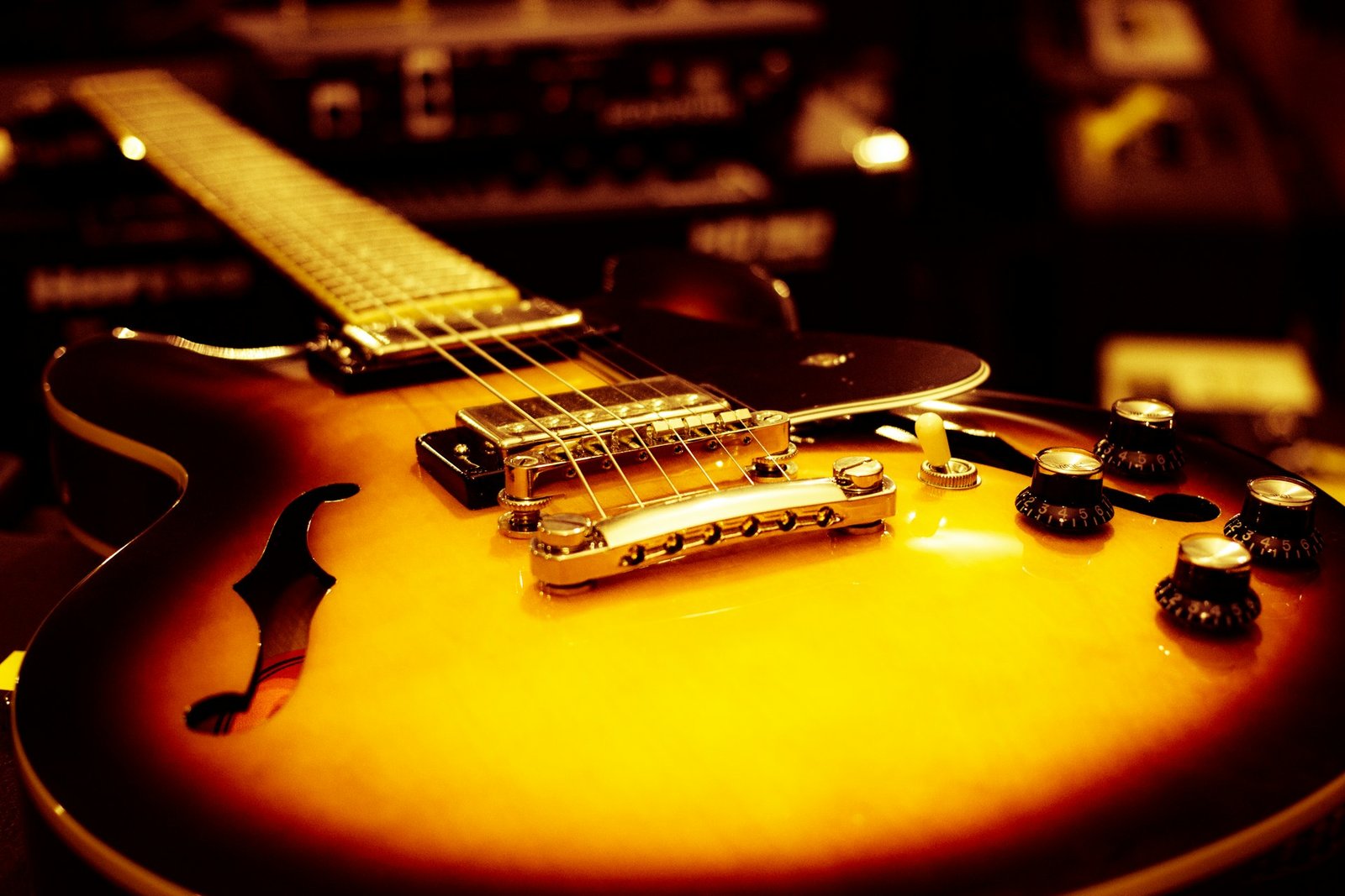 A sunburst hollow-body electric guitar with gold hardware in warm light